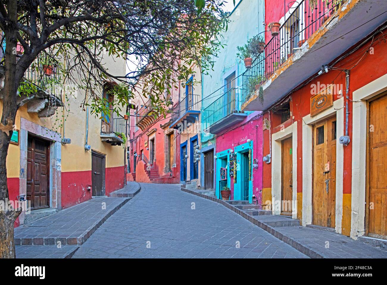 Boutique colorée de l'époque coloniale et maisons avec balcons dans une allée pavée de pierres coupées carrées dans la ville de Guanajuato, au centre du Mexique Banque D'Images