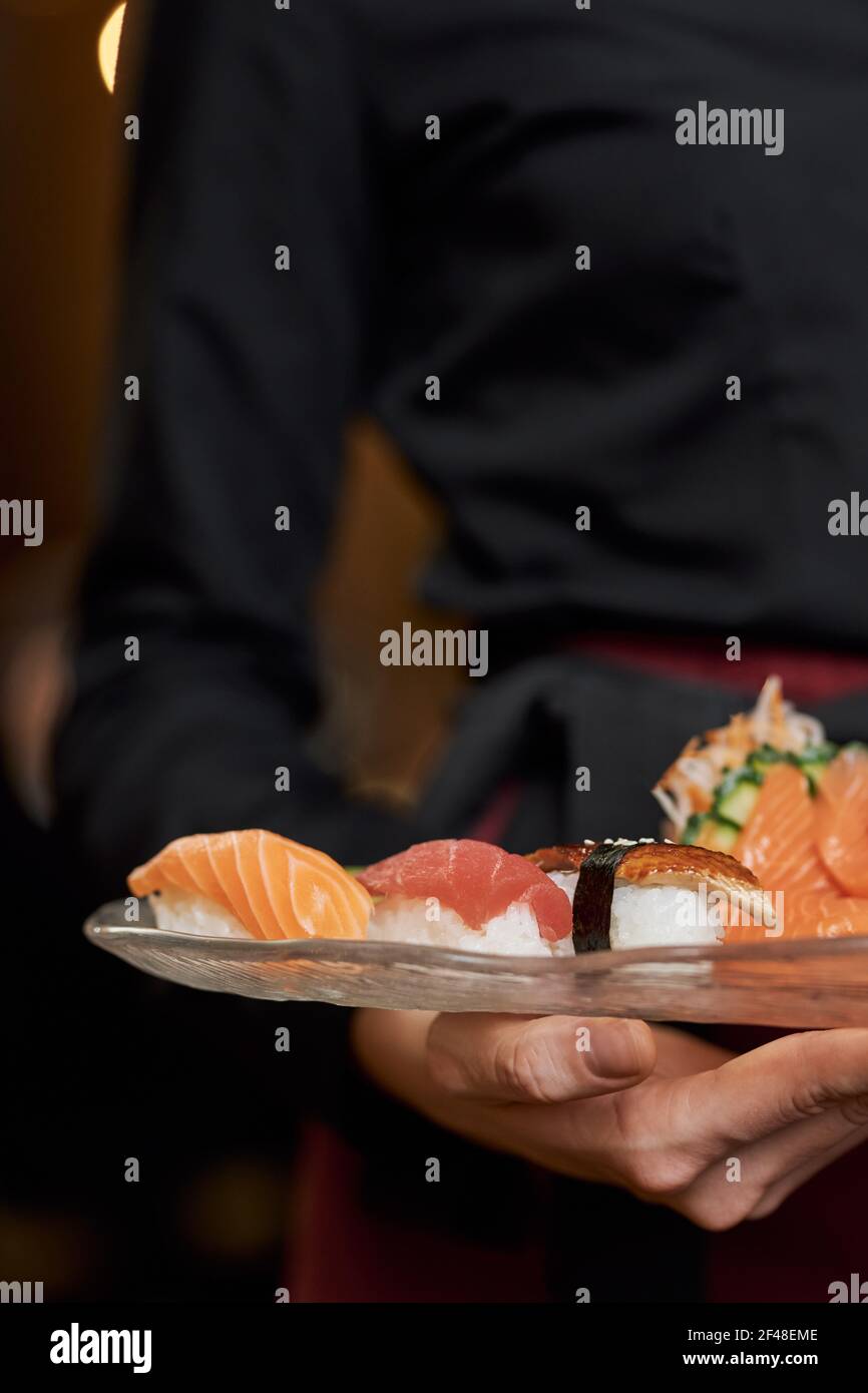 Des sushis appétissants sur les assiettes entre les mains du personnel du restaurant Banque D'Images