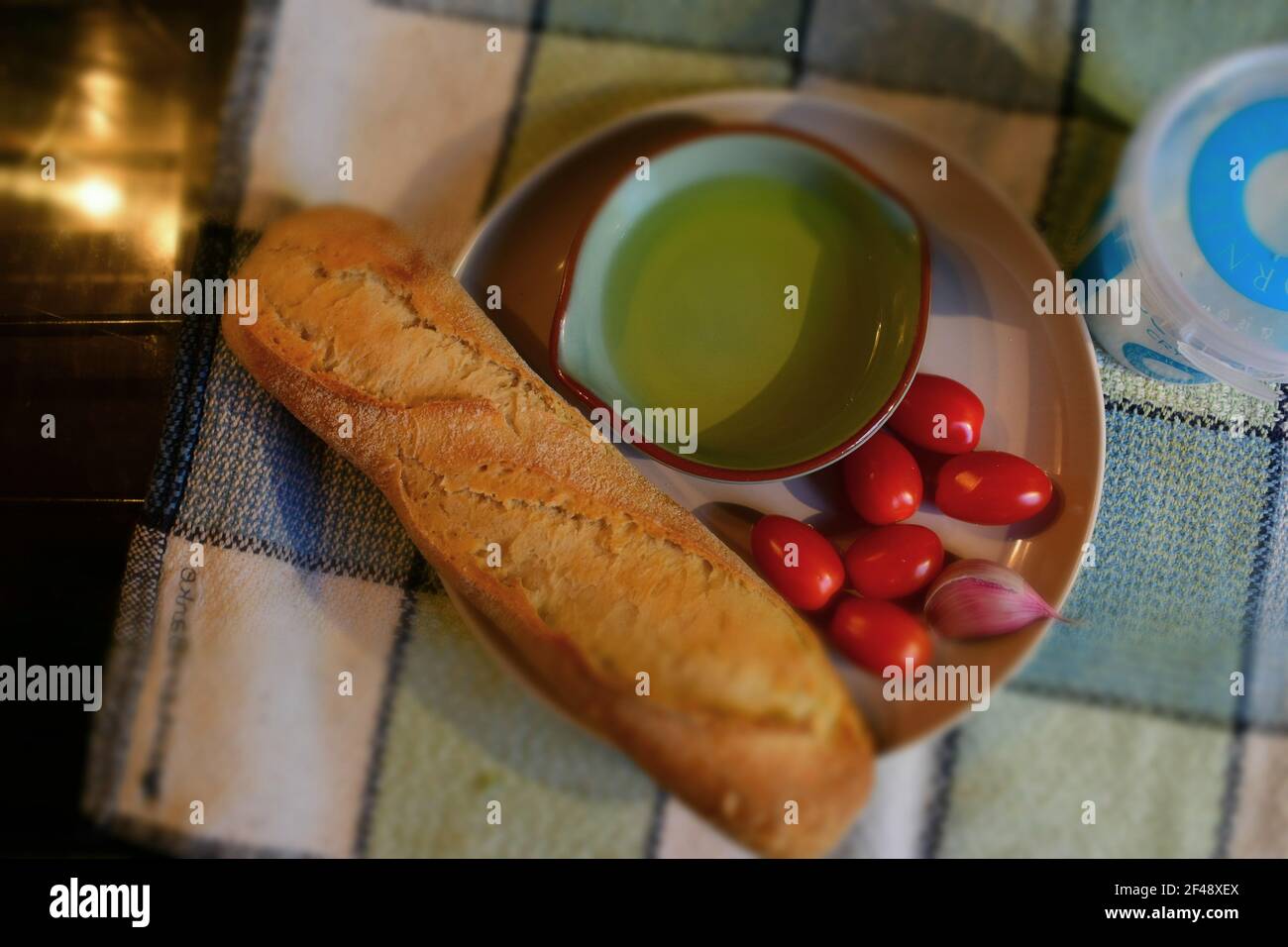 Ingrédients pour le pain de tomate catalan, pa amb tomàquet, sur une assiette - mini-tomates à plomb, baguette, ail, sel de mer et huile d'olive dans un plat peu profond. Banque D'Images