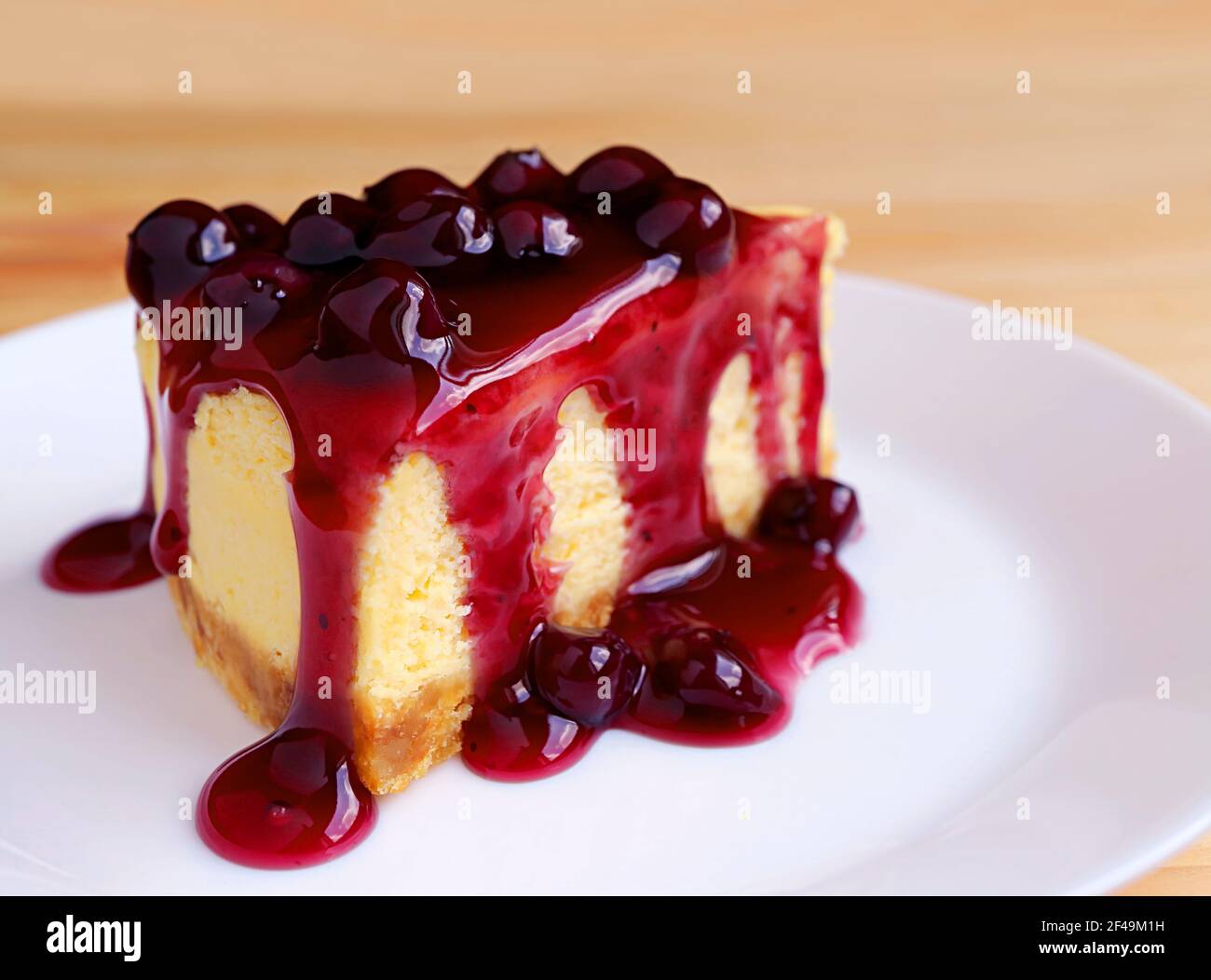 Tranche de cheesecake au four nappée d'une sauce aux myrtilles appétissante table en bois Banque D'Images