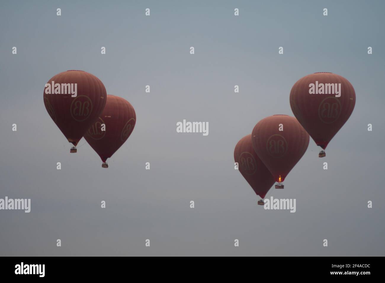 BAGAN, NYAUNG-U, MYANMAR - 2 JANVIER 2020 : cinq ballons rouges à air chaud s'élèvent dans le ciel ensemble pour les touristes Banque D'Images