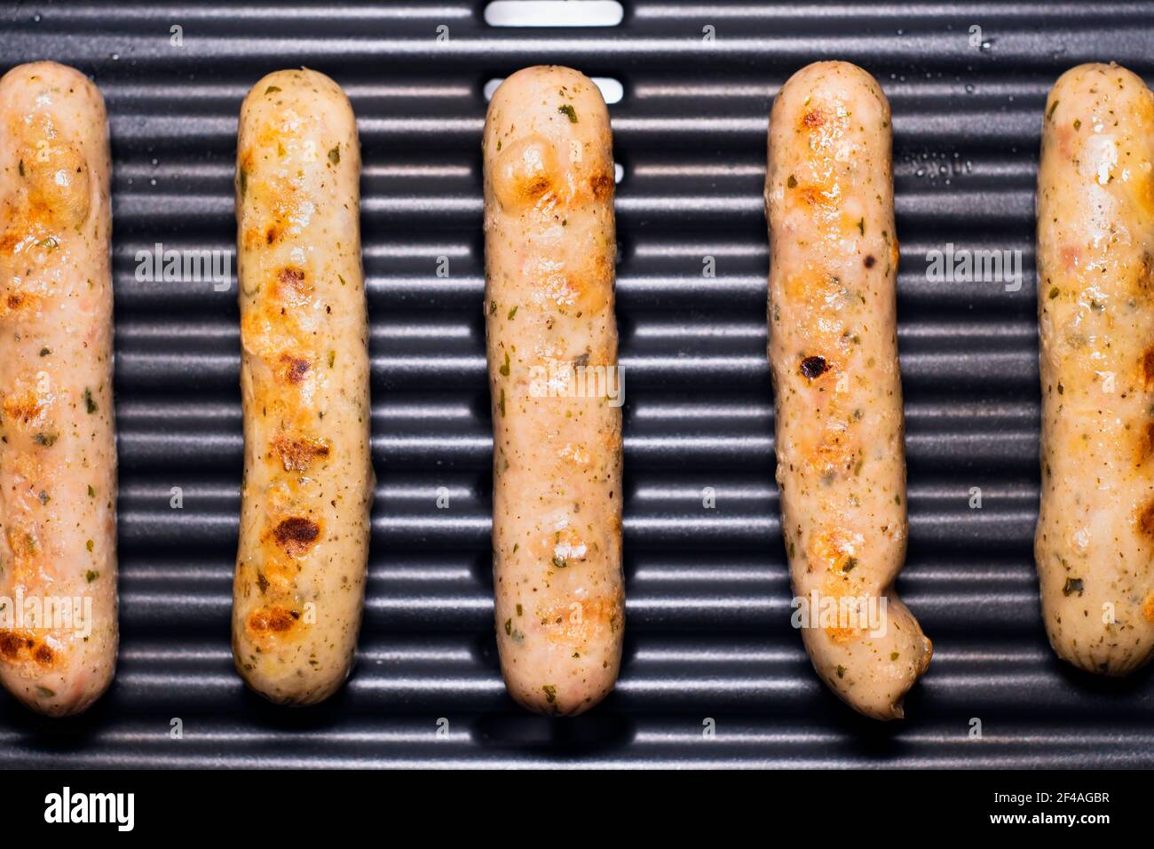 De délicieuses saucisses allemandes sur le barbecue électro-grill. De savoureuses saucisses se sirotant sur une grille électrique portable lors d'un pique-nique d'été, vue rapprochée. 4k Banque D'Images