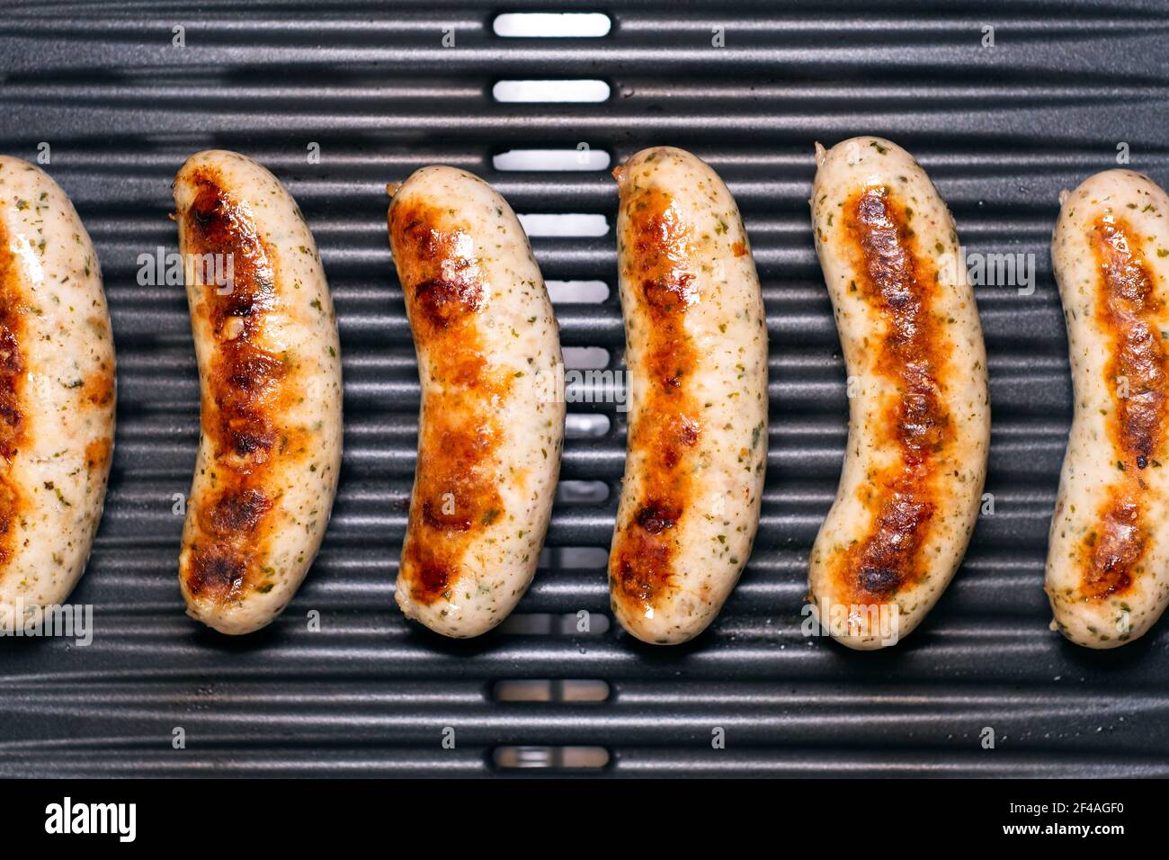 De délicieuses saucisses allemandes sur le barbecue électro-grill. De savoureuses saucisses se sirotant sur une grille électrique portable lors d'un pique-nique d'été, vue rapprochée. 4k Banque D'Images