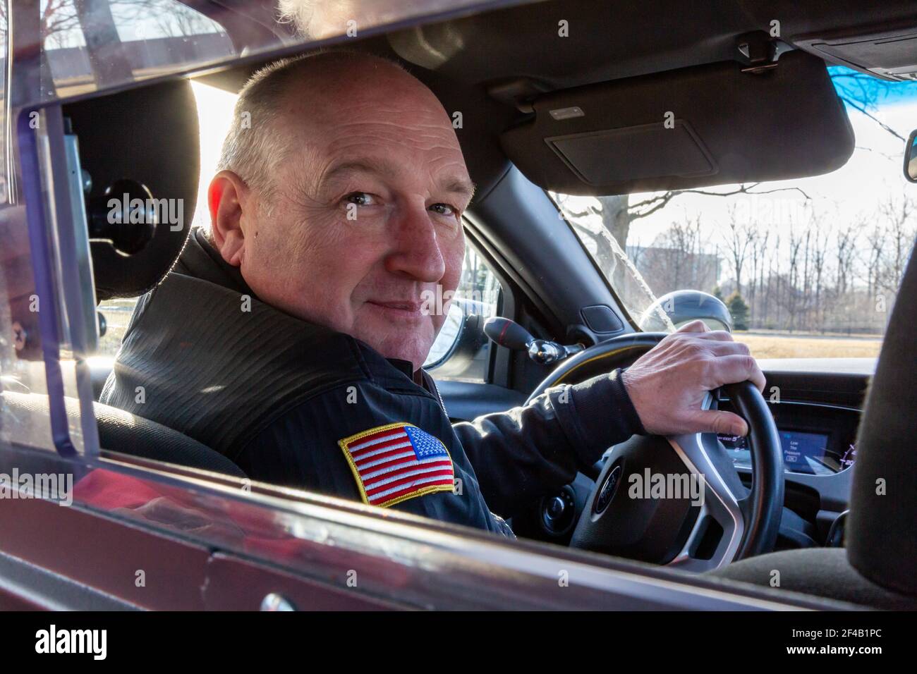 En regardant à travers la cage un policier en uniforme au volant d'une voiture d'équipe. Banque D'Images