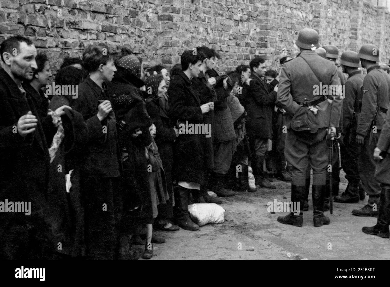 Soulèvement du ghetto de Varsovie - les Juifs capturés sont recherchés pour des armes et interrogés à côté du mur du ghetto avant d'être envoyés à la Umschlagplatz ca. 1943 Banque D'Images