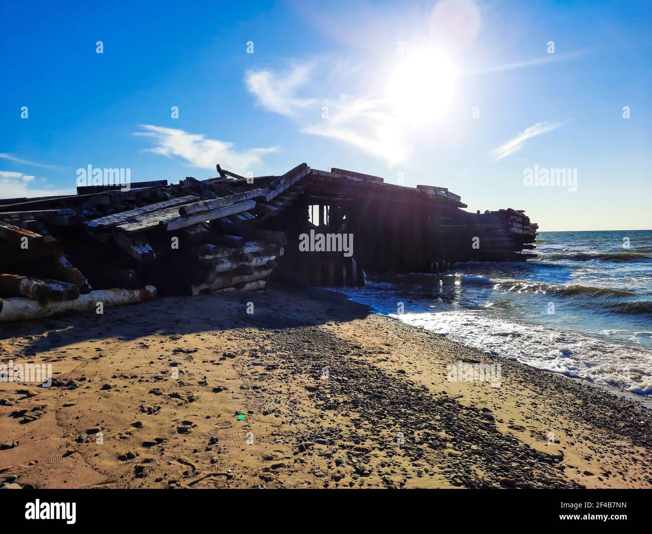 Jetée détruite sur le bord de mer contre le ciel bleu. Banque D'Images