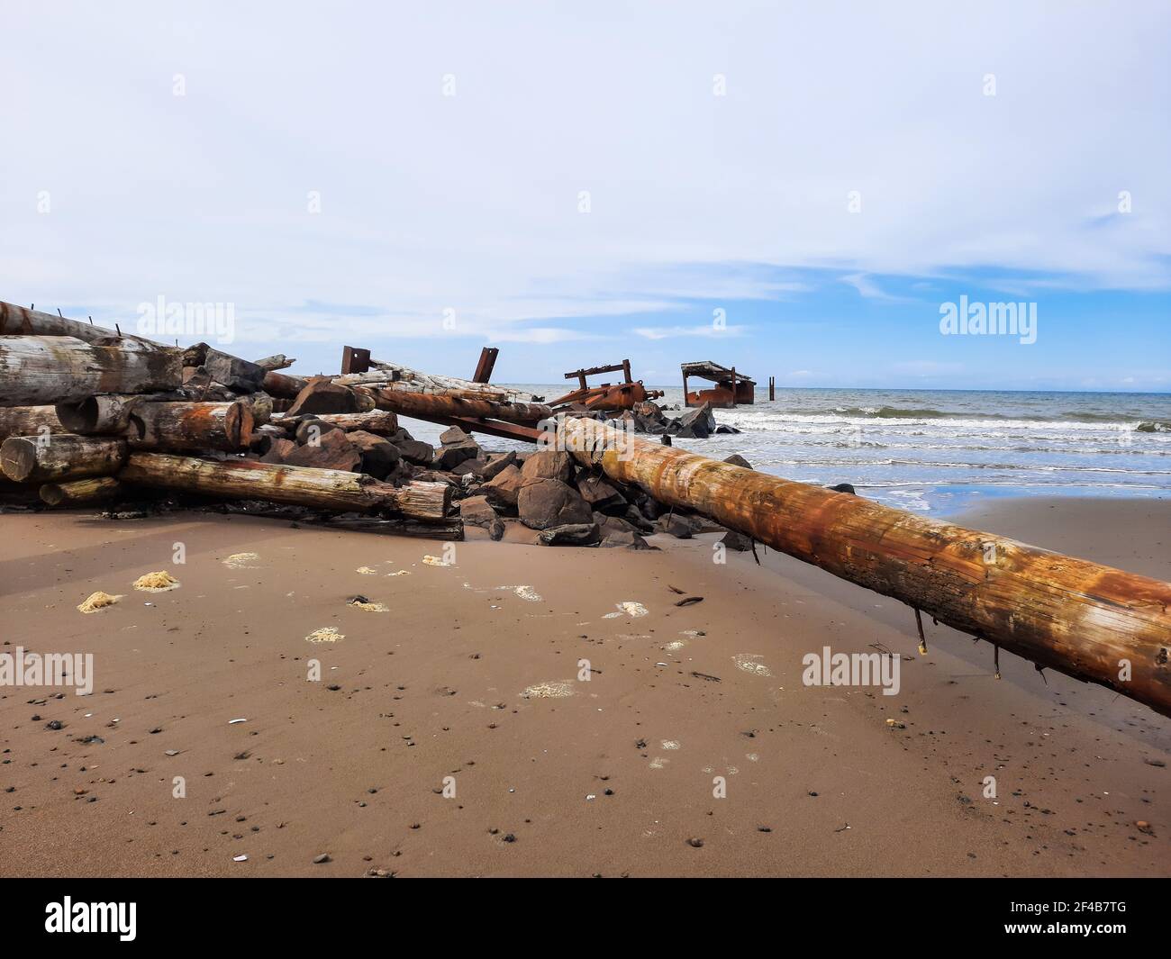 Jetée détruite sur le bord de mer contre le ciel bleu. Banque D'Images