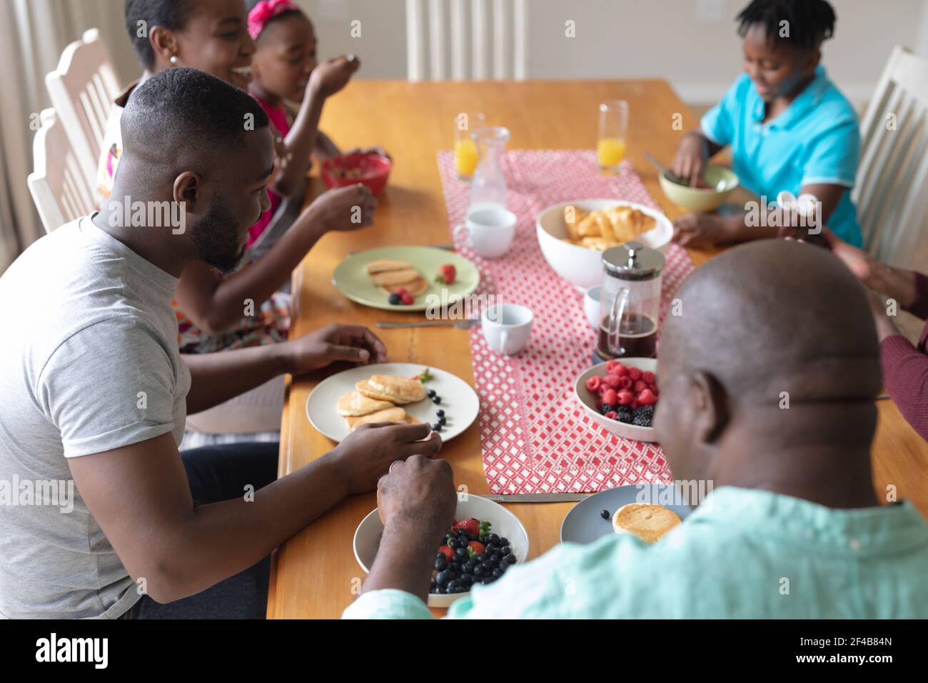 Heureux parents, grands-parents et petits-enfants afro-américains assis à table manger Banque D'Images