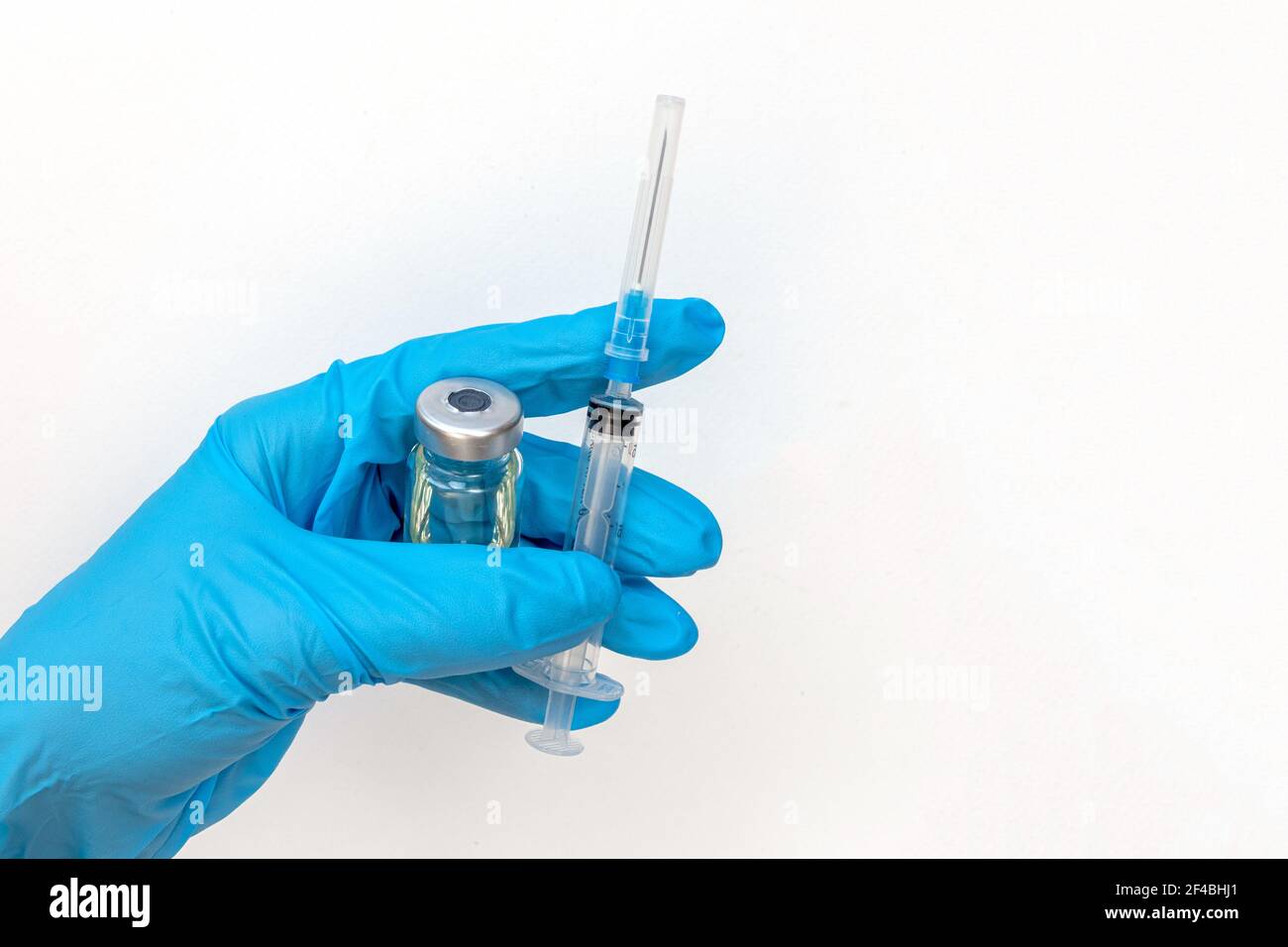 Main du médecin en gants bleus tenir le flacon avec un vaccin ou un médicament sur fond blanc. Concept d'étude de vaccination contre le coronavirus. Banque D'Images