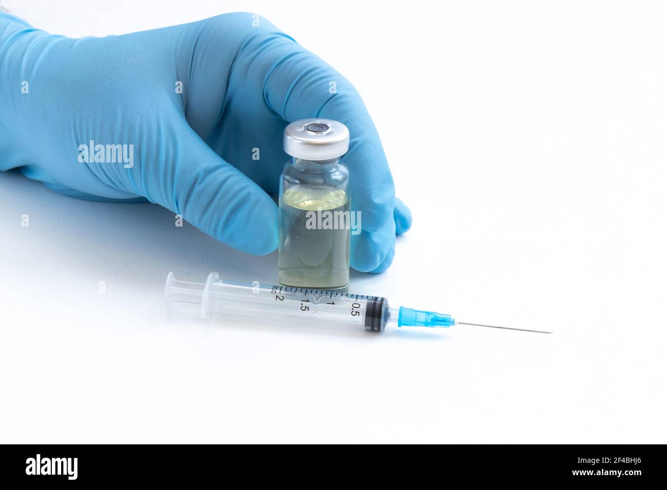 Main du médecin en gants bleus tenir le flacon avec un vaccin ou un médicament sur fond blanc. Concept d'étude de vaccination contre le coronavirus. Banque D'Images