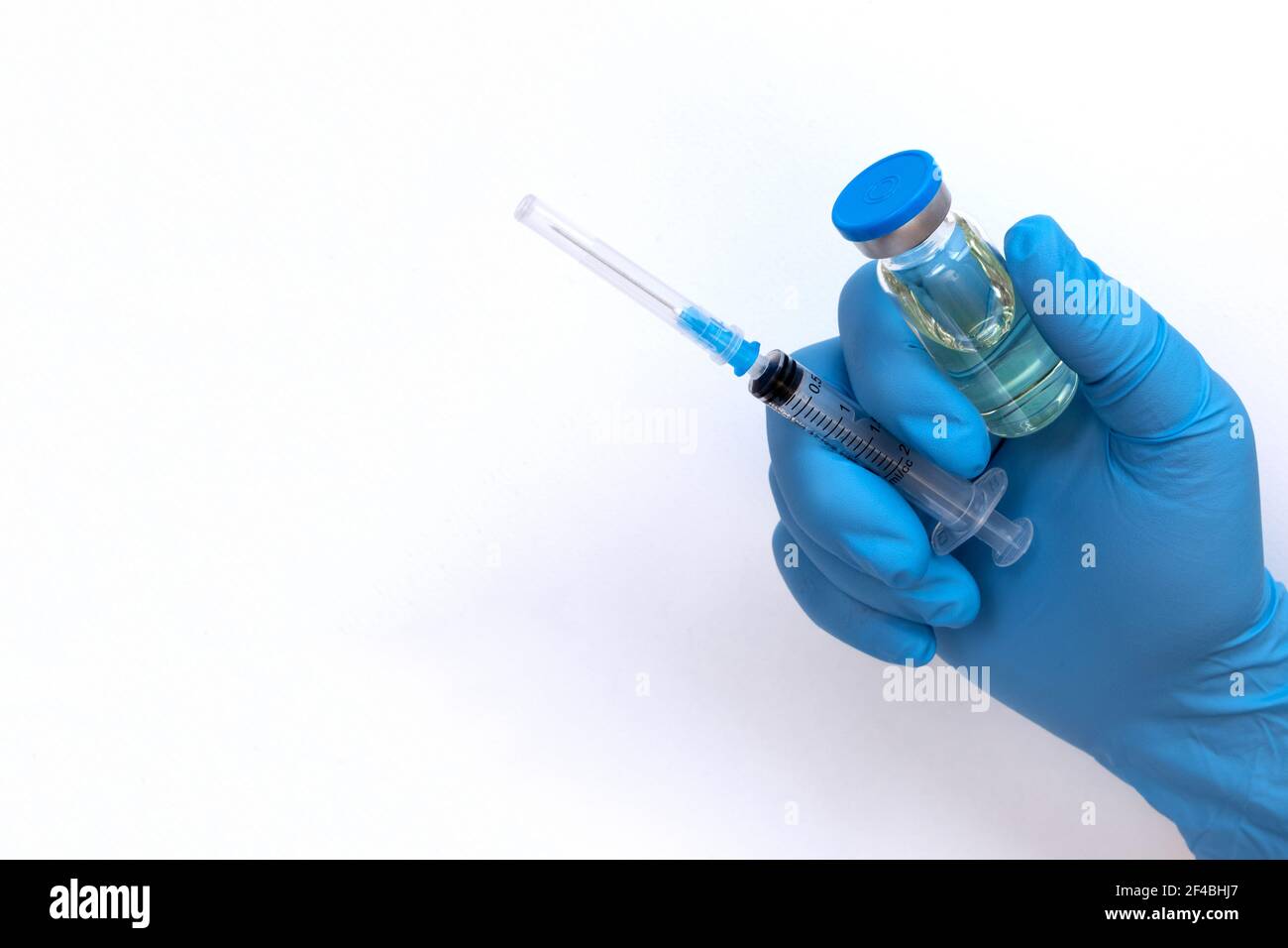 Main du médecin en gants bleus tenir le flacon avec un vaccin ou un médicament sur fond blanc. Concept d'étude de vaccination contre le coronavirus. Banque D'Images