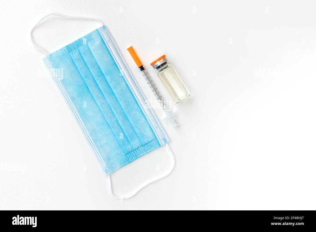 Flacon de vaccin, seringues et masque chirurgical isolé sur fond blanc, posé à plat avec espace pour le texte. Concept de vaccin contre le coronavirus. Vaccination et immu Banque D'Images