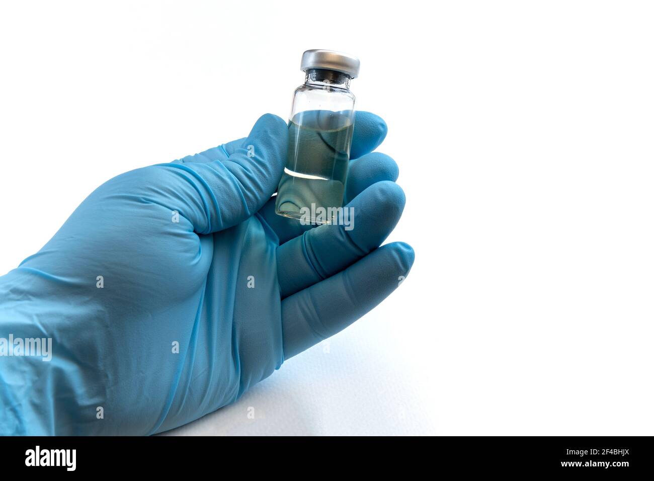 Main du médecin en gants bleus tenir le flacon avec un vaccin ou un médicament sur fond blanc. Concept d'étude de vaccination contre le coronavirus. Banque D'Images