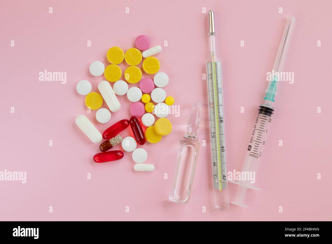 Bouteille en verre avec médicaments. Thermomètre, seringue et pilule pour traiter les rhumes sur fond rose. Remèdes contre le froid. Concepts médicaux et médicaments. Top vie Banque D'Images