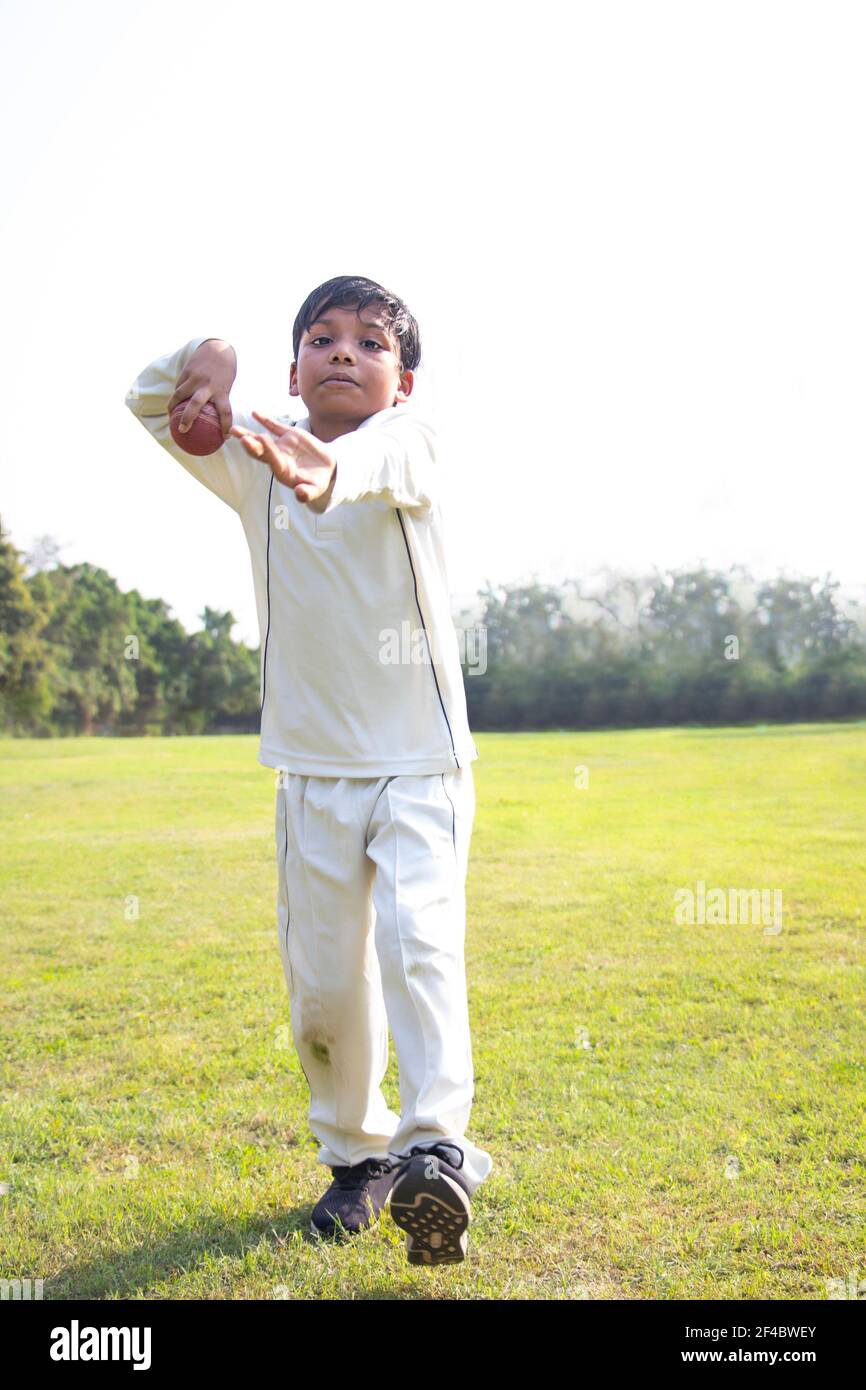 Un jeune garçon fait un tour de bowling dans un cricket Banque D'Images