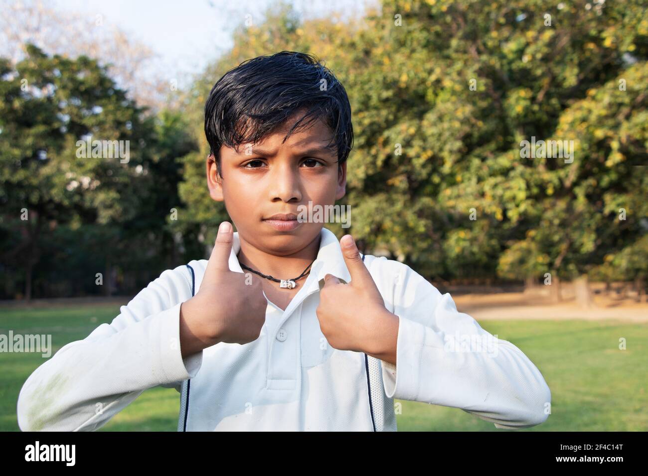 Un garçon dans l'uniforme de cricket et de pointage Banque D'Images
