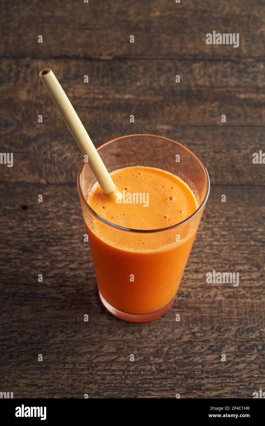 Un verre de jus de carotte avec un bambou respectueux de l'environnement paille Banque D'Images