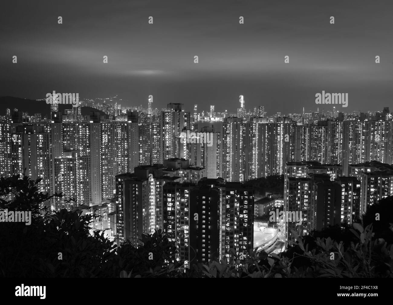 Vue nocturne des immeubles résidentiels de Kowloon, Hong Kong en noir et blanc. Les nuages sont éclairés par des bâtiments éclairés. Banque D'Images