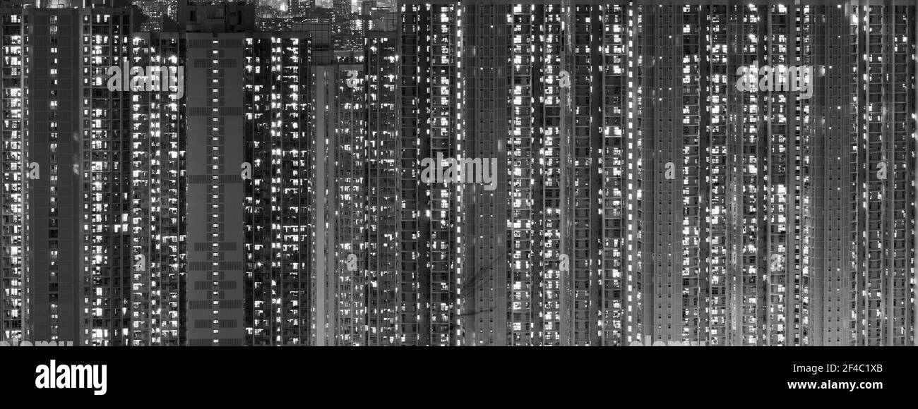 Vue de nuit sur les immeubles résidentiels de Kowloon, Hong Kong. Des centaines de fenêtres lumineuses sont visibles. Noir et blanc. Banque D'Images