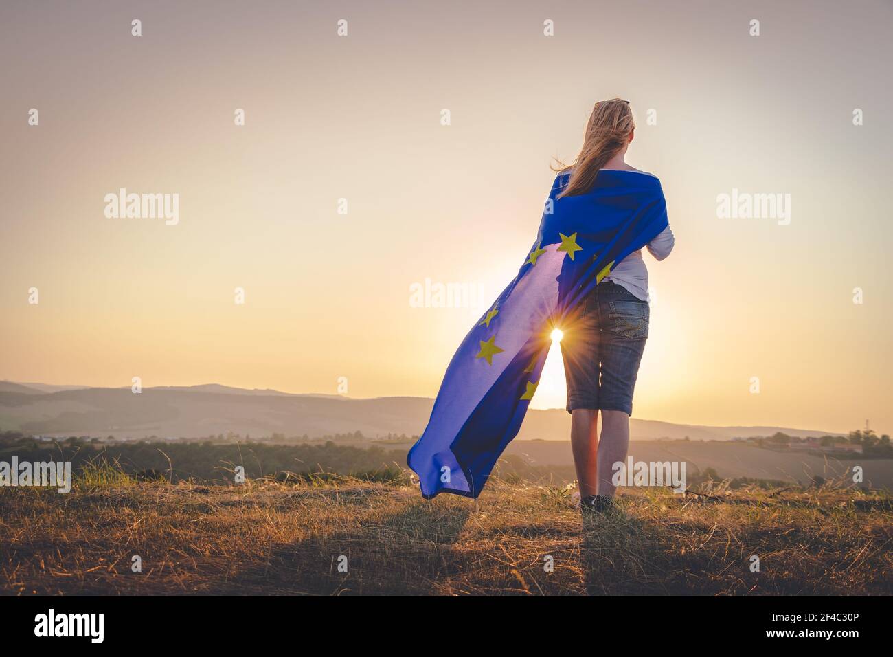 Regardez l'avenir de l'Europe. Femme caucasienne avec drapeau de l'Union européenne regardant le coucher de soleil à l'extérieur. Banque D'Images