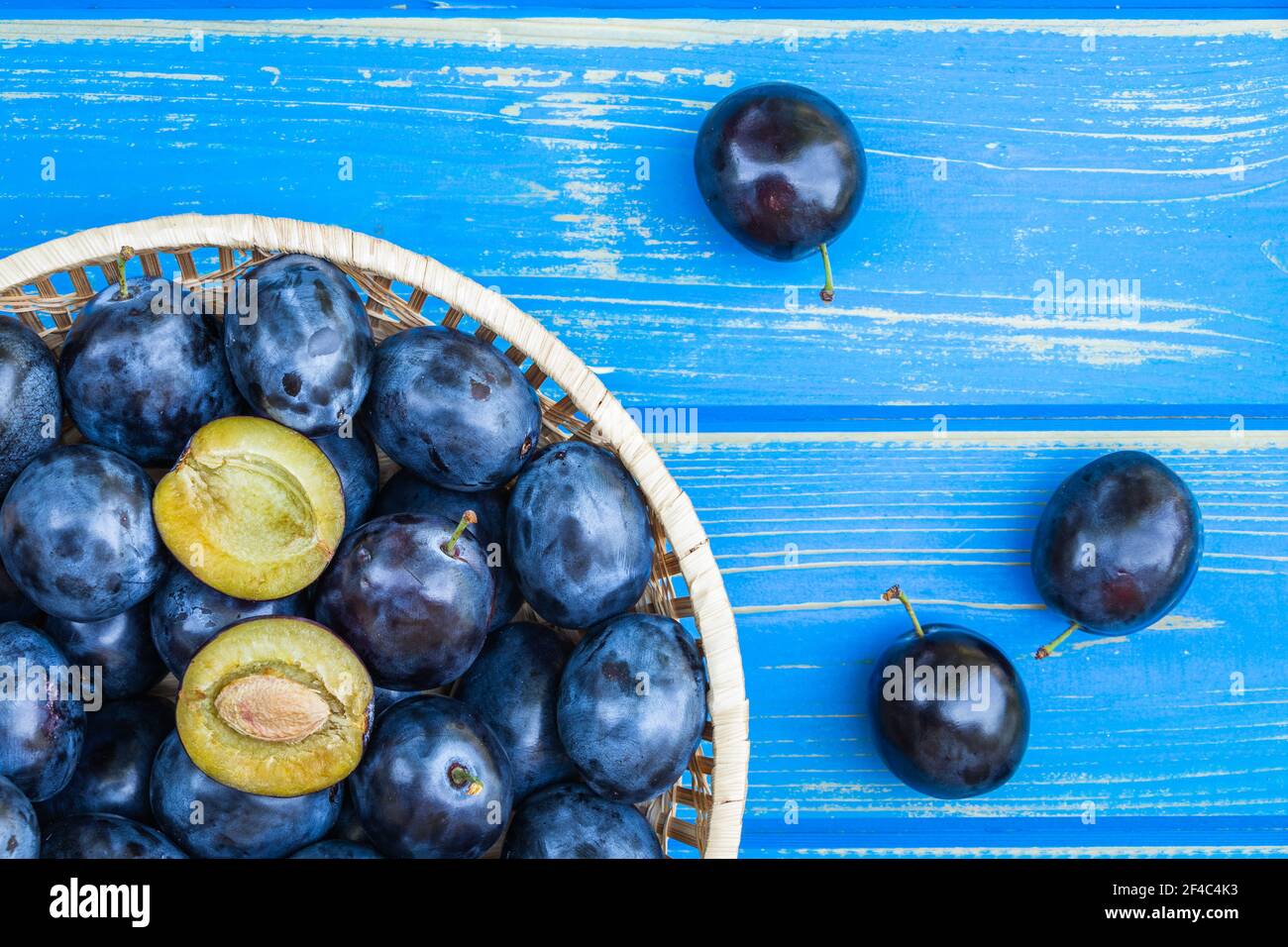 Prunes mûres dans un bol sur une table en bois bleu, juste au-dessus. Fruits prune fraîchement récoltés Banque D'Images