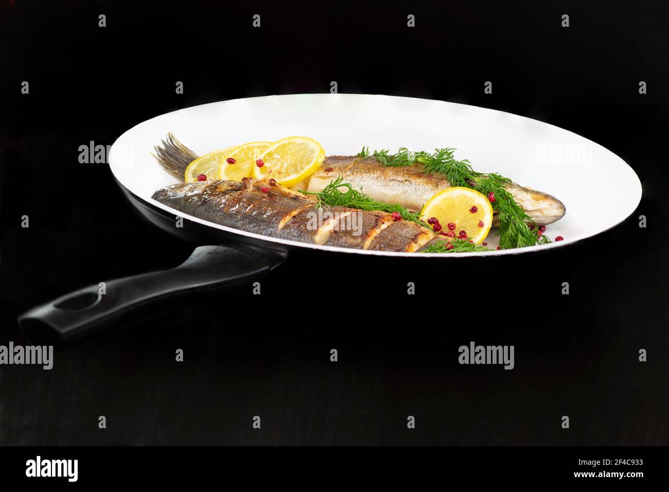 Deux plats de bar de la mer dans la casserole avec aneth, citron et grains de poivre rose Banque D'Images