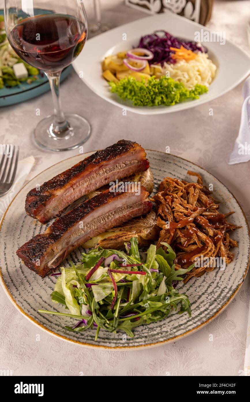 Côtes de rechange grillées chaudes épicées servies avec de la laitue verte fraîche à la table du restaurant Banque D'Images