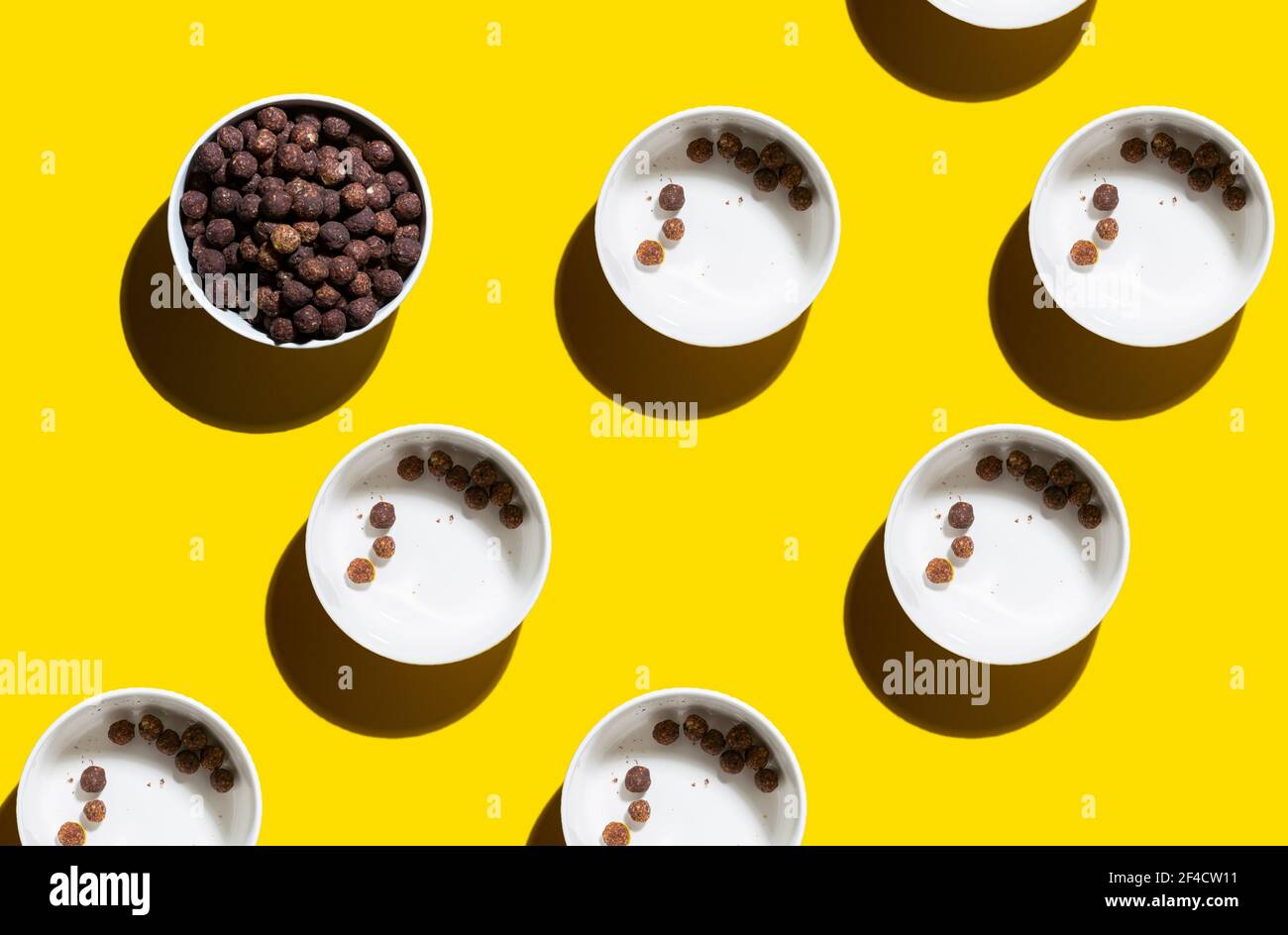 motif lumineux jaune. boules de maïs chocolat pour le petit déjeuner dans une assiette en céramique blanche. ombres dures Banque D'Images