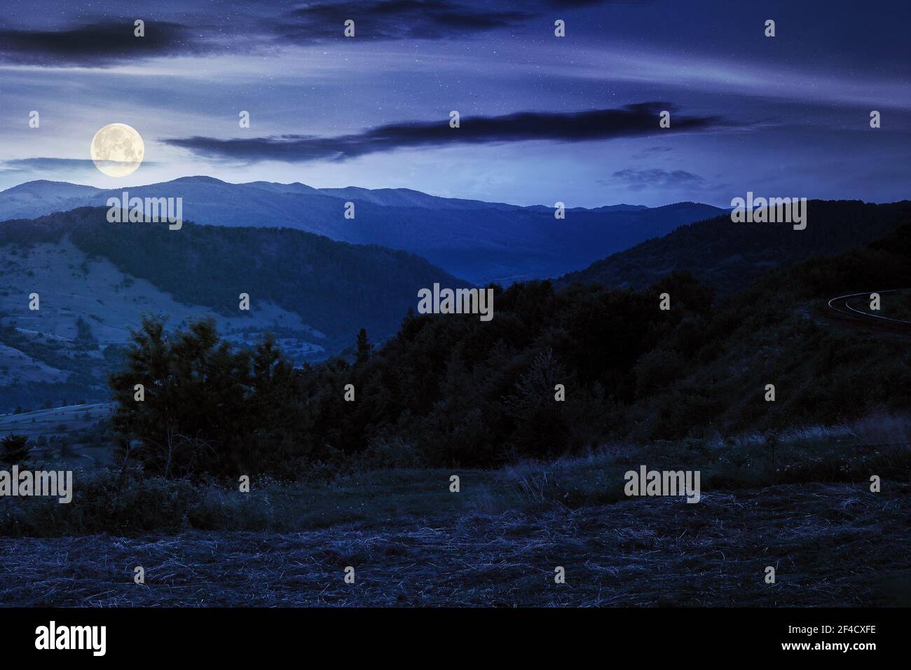 paysage rural montagneux la nuit. prairie herbacée au sommet d'une colline. nuages au-dessus de la crête en pleine lune. vue sur la vallée éloignée Banque D'Images paysage rural montagneux la nuit. prairie herbacée au sommet d'une colline. nuages au-dessus de la crête en pleine lune. vue sur la vallée éloignée Banque D'Images