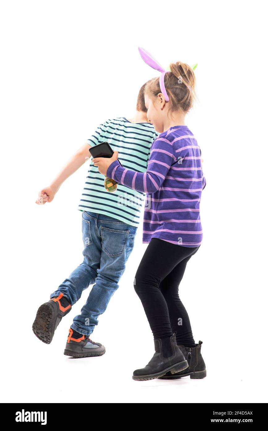 Garçon et fille jouant à la chasse et à la capture de jeu avec le téléphone portable et les oreilles de lapin chapeau. Corps entier isolé sur fond blanc Banque D'Images