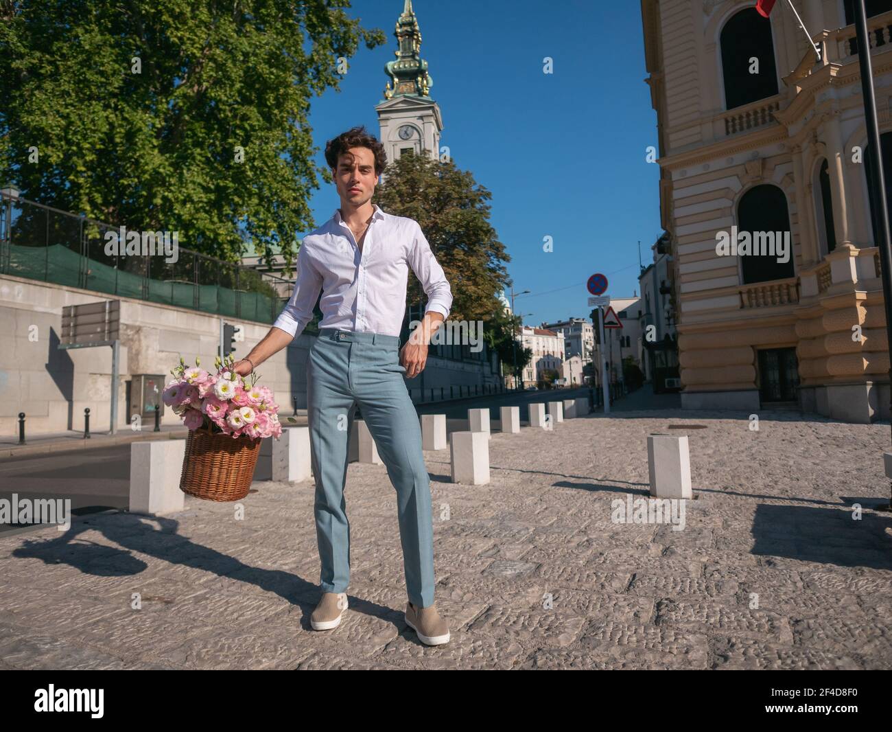 Joyeux jeune homme, élégant et décontracté, portant un panier de fleurs. Banque D'Images