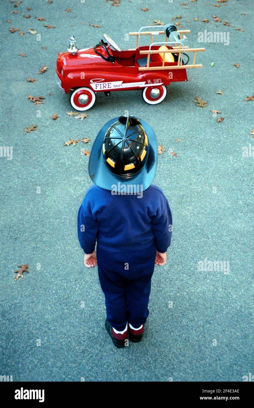 Jeune garçon dans un chapeau de pompier avec une voiture à pédale de camion  de pompiers Photo Stock - Alamy