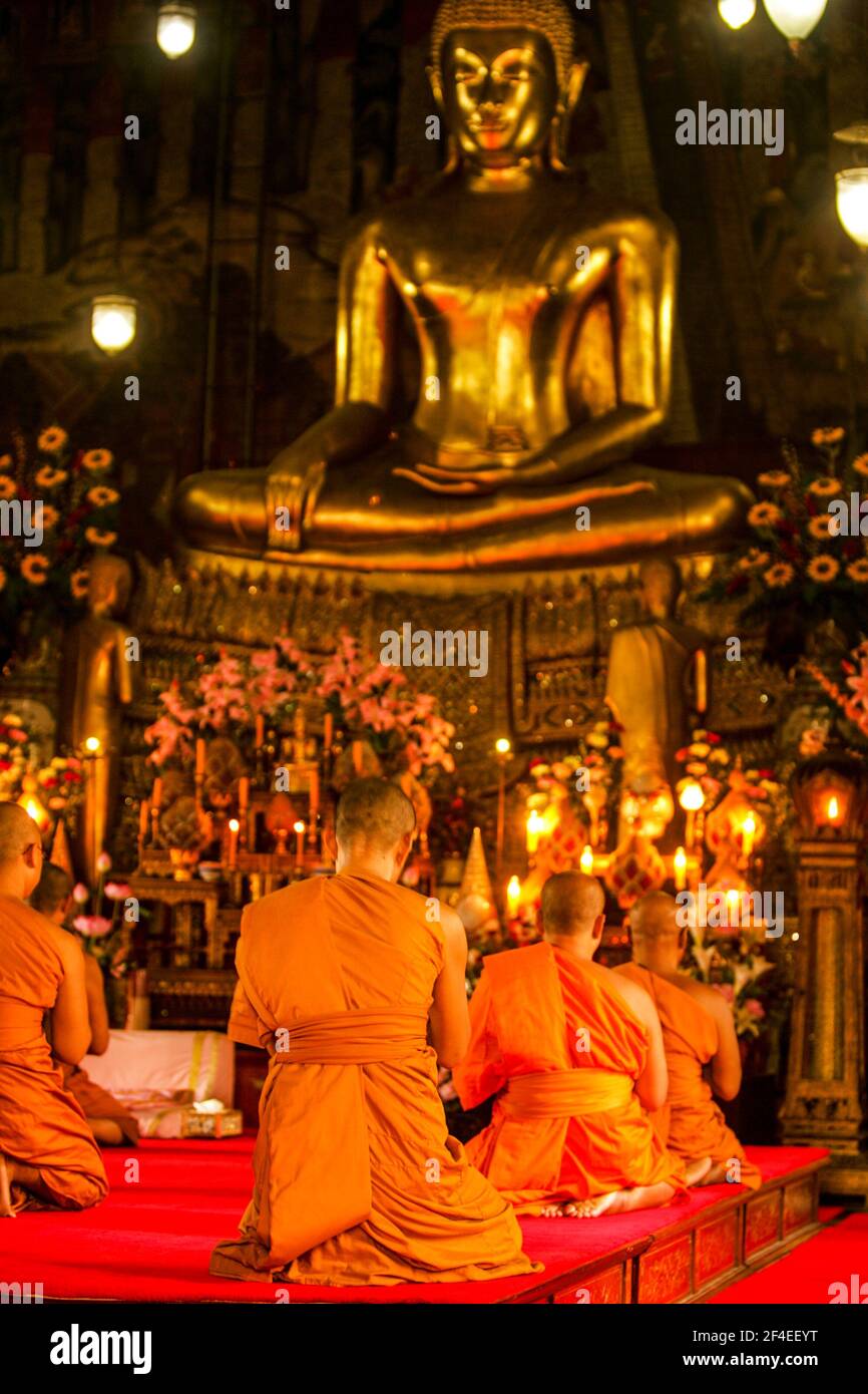 Les moines bouddhistes s'agenouillent devant une statue de Bouddha des Lumières « Call the Earth to Witness » à Bangkok, en Thaïlande. Banque D'Images