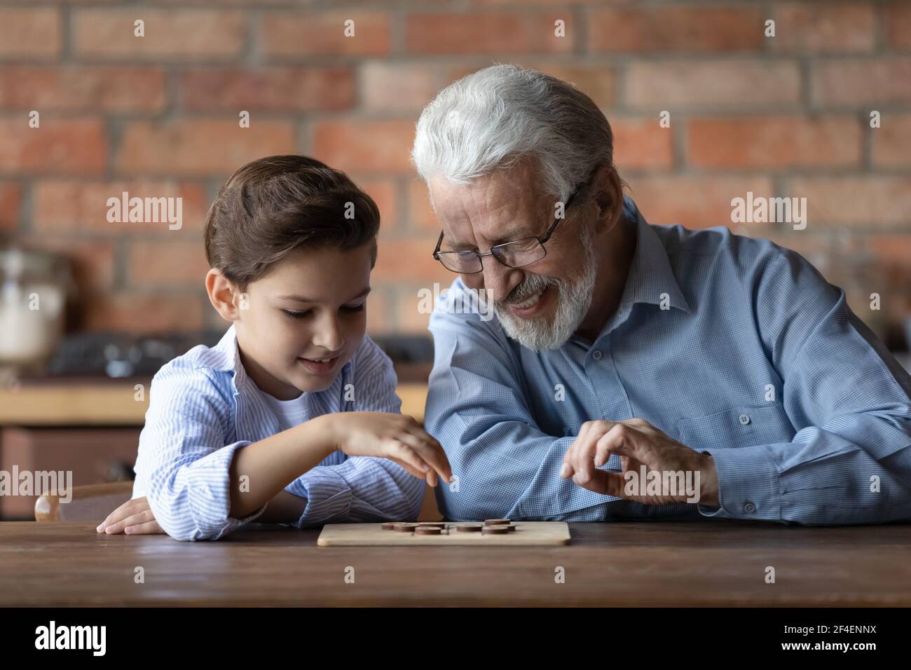 Joyeux grand-père mature et petit-fils jouent des dames Banque D'Images