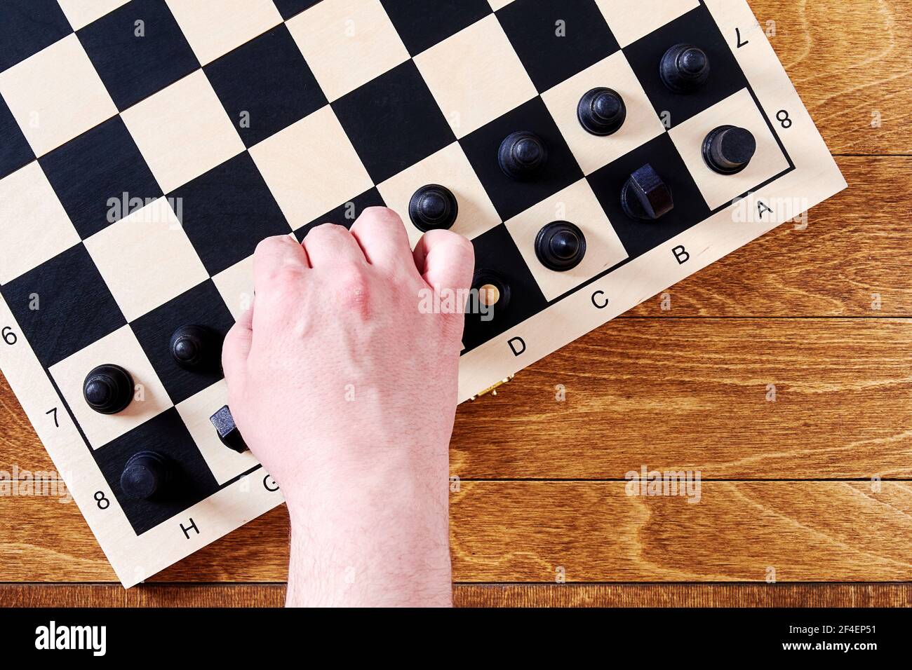 Les joueurs prennent un pion noir pour faire un mouvement d'échecs sur le plateau. Activités de loisirs et jeux intellectuels Banque D'Images