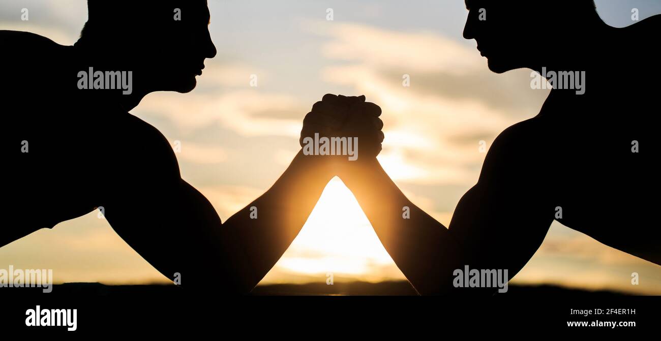 Deux hommes luttant. Silhouette de mains qui rivalisent en force. Comparaison rivalité, vs, défi, force. Coucher de soleil, lever du soleil. Rivalité, gros plan Banque D'Images