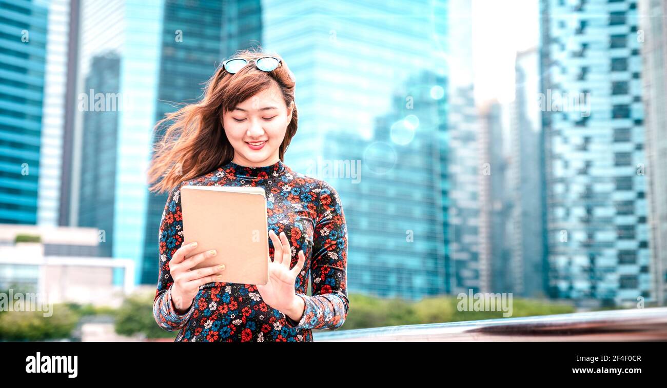 Jeune femme asiatique utilisant un appareil électronique dans une ville moderne - Concept de style de vie technologique avec une fille s'amusant avec une tablette pc périphérique Banque D'Images