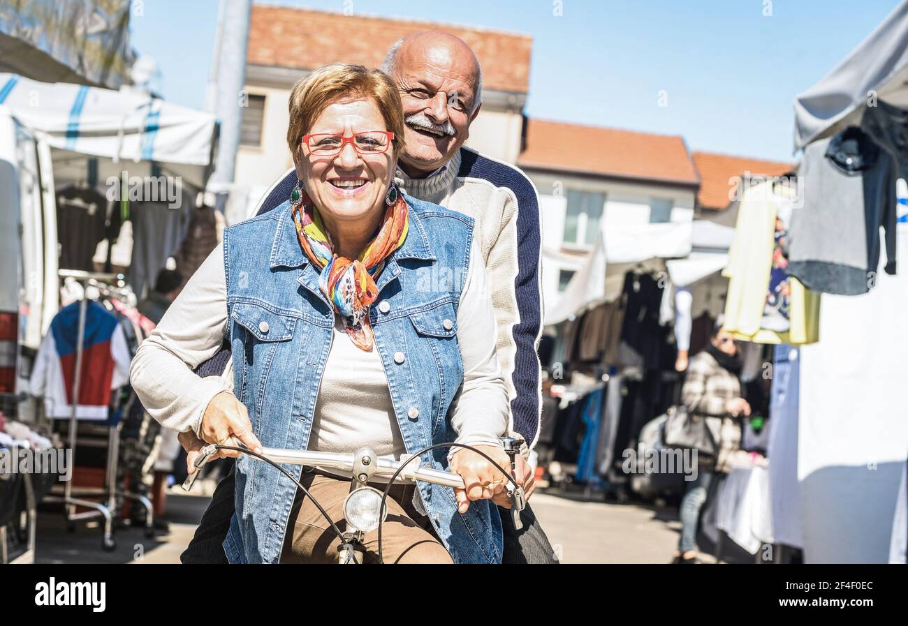 Couple senior heureux s'amusant à vélo sur le marché de la ville - Active ludique vieux concept équitation vélo au moment de la retraite - la joie de vivre au quotidien Banque D'Images