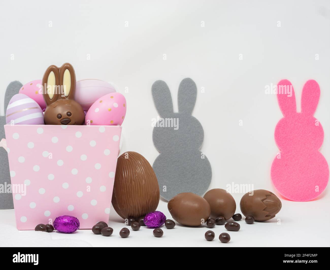 Ensemble de chocolats de Pâques, avec un lapin et des œufs de chocolat, sur fond blanc avec des silhouettes de lapin. Banque D'Images