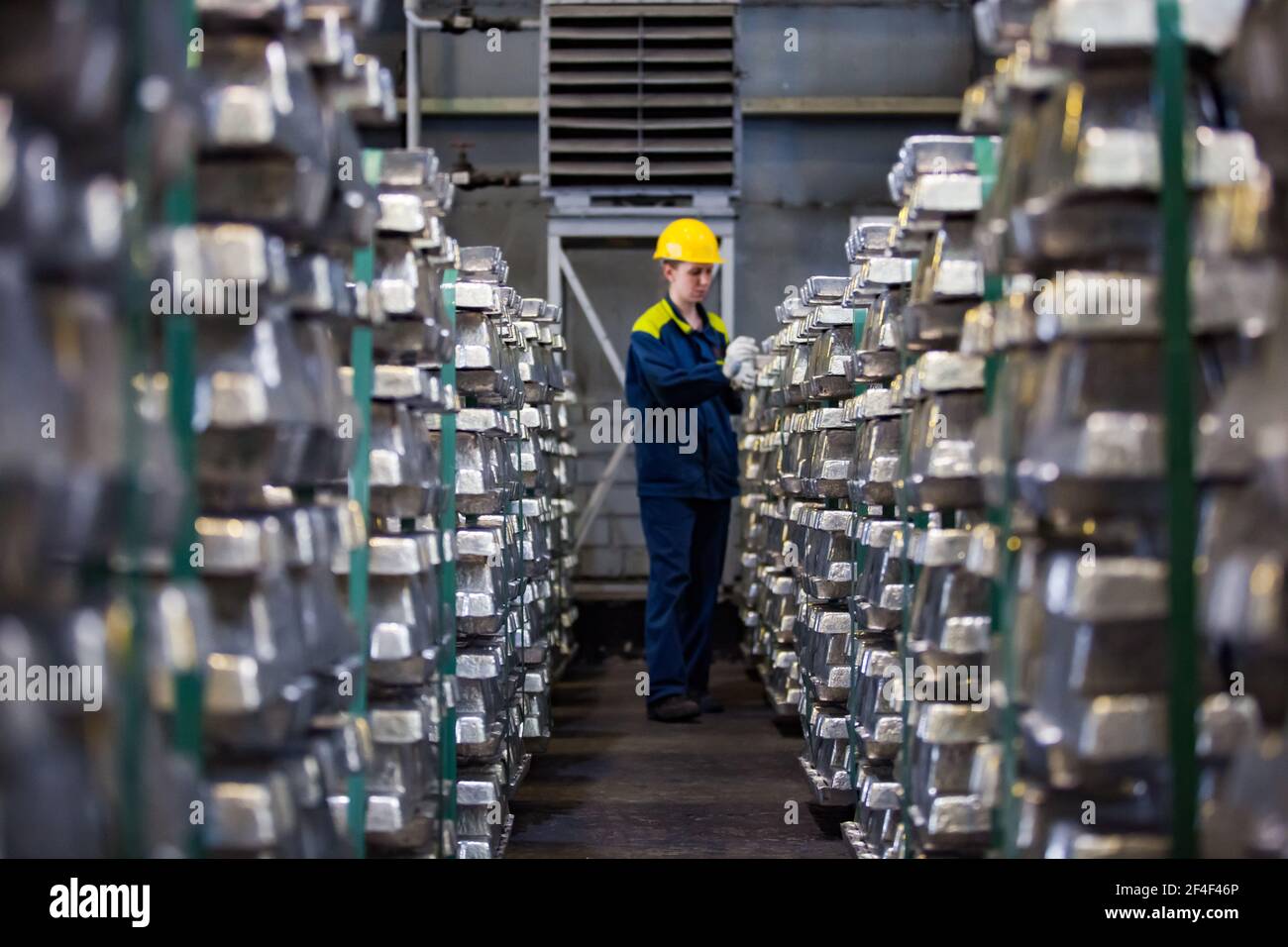 Pavlodar, Kazakhstan - mai 05 2012 : usine d'électrolyse de l'aluminium. Entrepôt de lingots prêts. Femme travailleuse en casque de sécurité jaune et en vêtement de travail bleu. Concentrez-vous sur moi Banque D'Images
