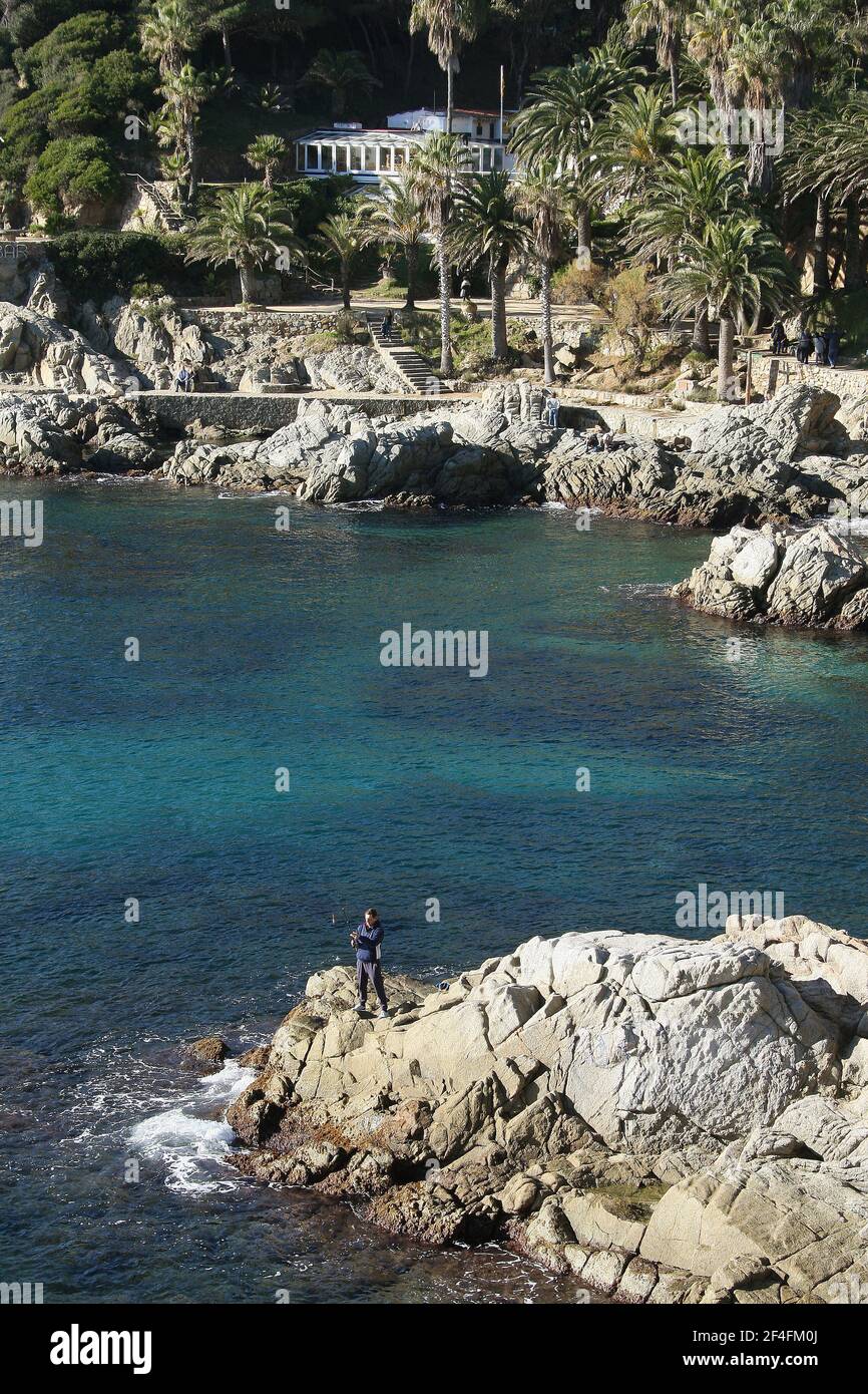 Un pêcheur sur un rocher dans la ville balnéaire de Lloret de Mar sur la Costa Brava près de Calella in Catalogne Espagne UE 2019 Banque D'Images