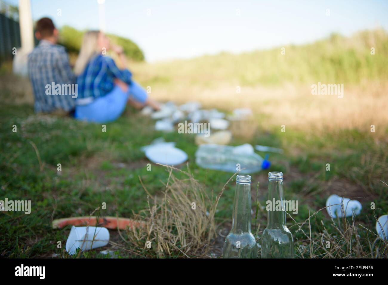 Déchets sur la plage. Jeune couple se reposant sur la plage à côté d'une pile de déchets. Concept humain et nature Banque D'Images