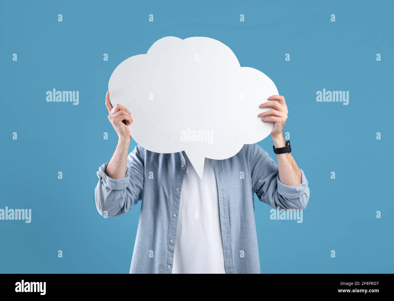 Jeune homme sans visage couvrant son visage avec une bulle de discours sur fond bleu studio, maquette pour le design Banque D'Images