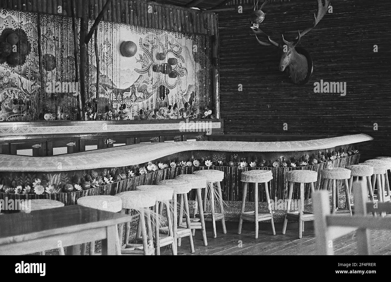 Vue panoramique d'un bar à thème tropical, avec un comptoir incurvé, des tabourets tissés, une toile de fond ornée de perles et une tête de cerf montée sur le mur, parc national de la Guira, Pinar del Rio, Cuba, 1964. () Banque D'Images