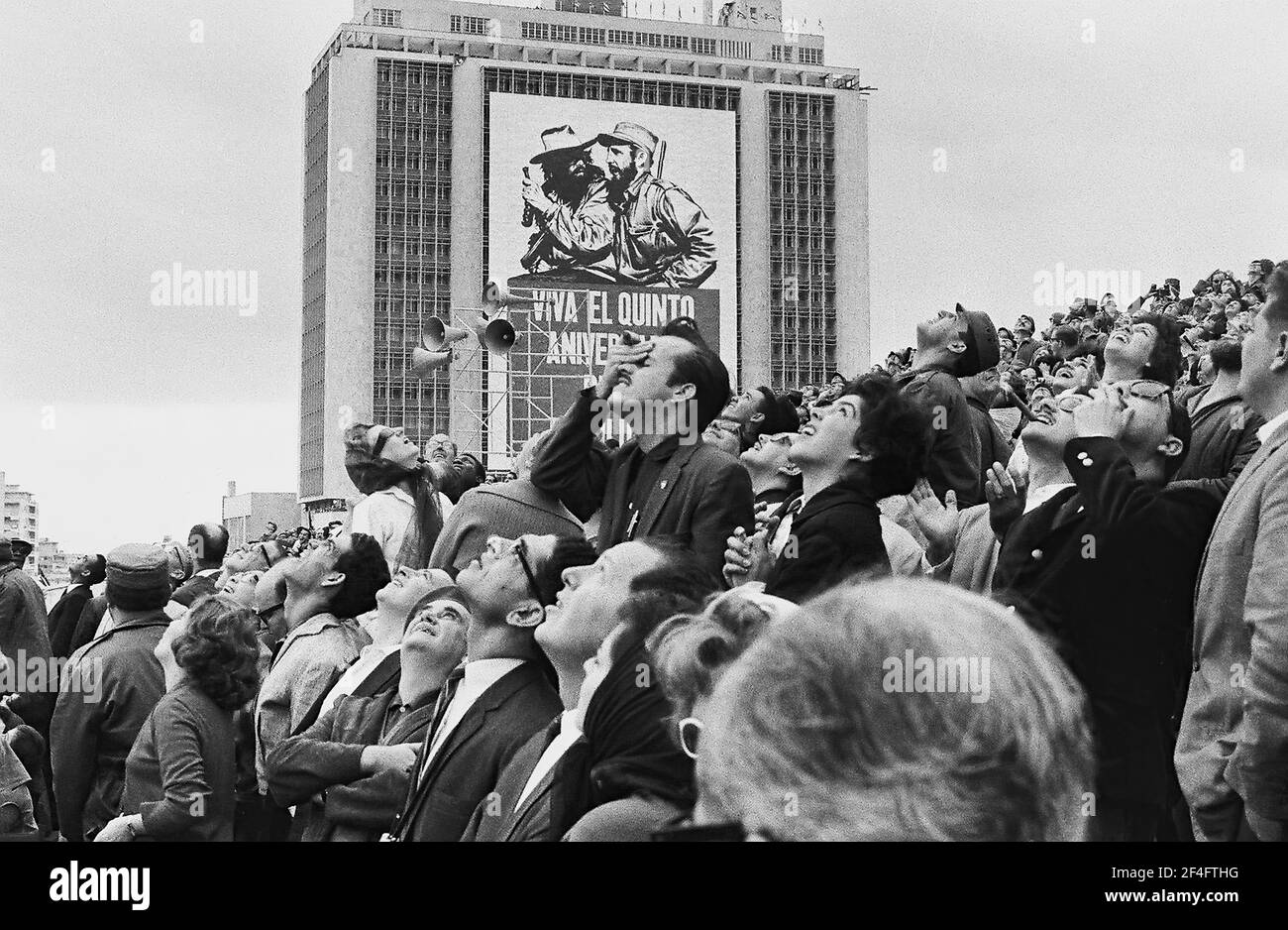 Invités sur la tribune présidentielle pendant la parade militaire, la Havane, Cuba, avec affiche de propagande sur le bâtiment en arrière-plan, 1963. De la collection de photographies Deena Stryker. () Banque D'Images