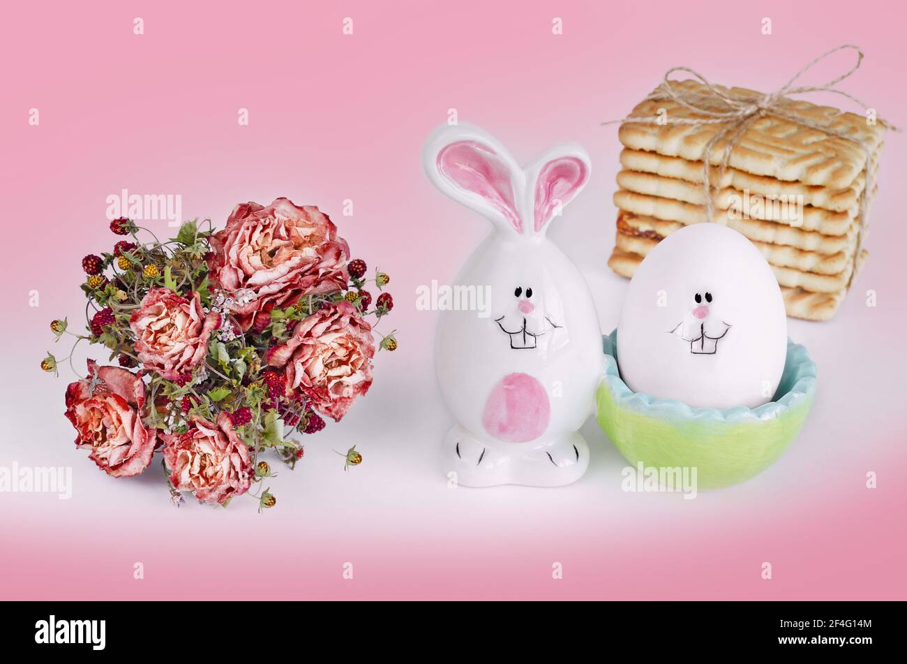 Un lapin de Pâques et un œuf avec un visage sur fond rose et blanc. Le concept de Pâques Banque D'Images