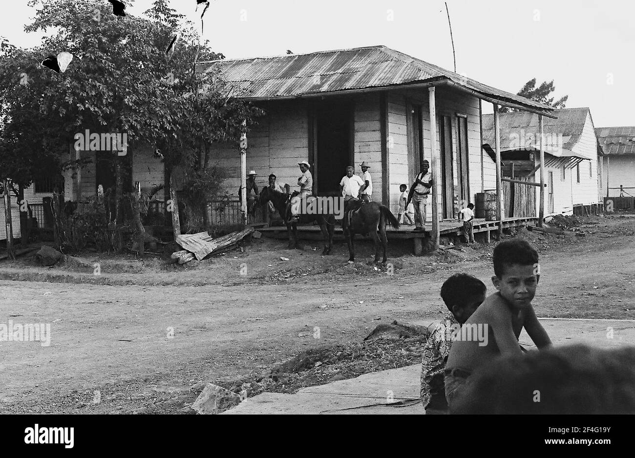 Des enfants sont rassemblés autour d'un bâtiment de fortune à Biran, Cuba, province de Holguin, 1963. De la collection de photographies Deena Stryker. () Banque D'Images