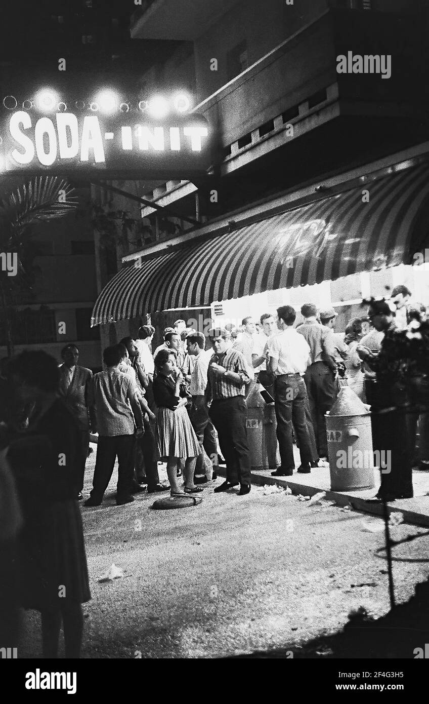 Vue de nuit d'un grand nombre de clients se tenant à l'extérieur d'un stand de glace à Vedado, la Havane, Cuba, 1964. De la collection de photographies Deena Stryker. () Banque D'Images