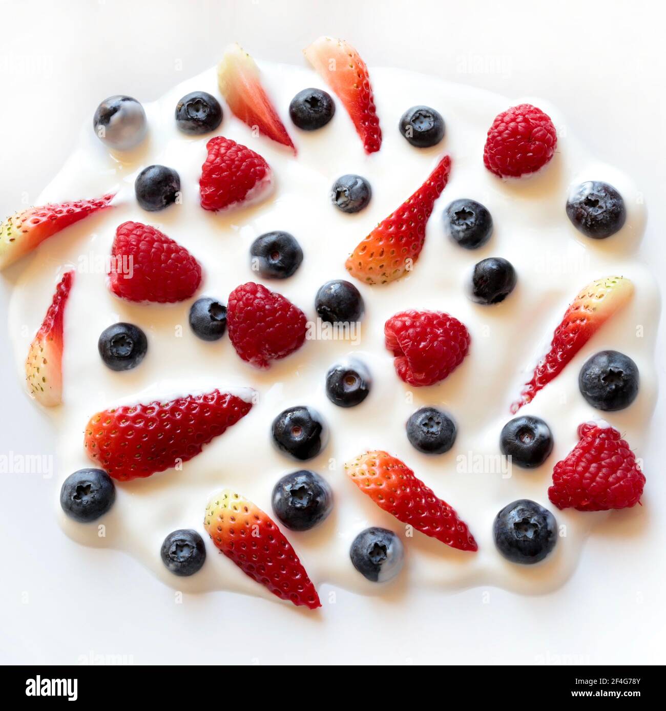 Yaourt et fruits. Yaourt aux myrtilles, fraises, framboises et amandes sur fond blanc. Directement au-dessus. Banque D'Images