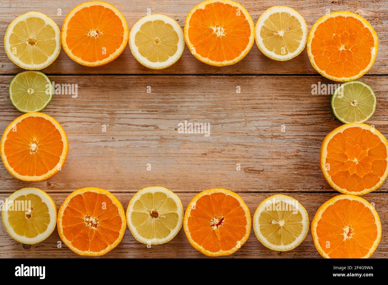 Des oranges, des limes et des citrons glissent sur une table en bois vue d'en haut.Beautiful Arrière-plan avec des fruits frais moitié coupé.alimentation saine vitamine C.Tropica d'été Banque D'Images